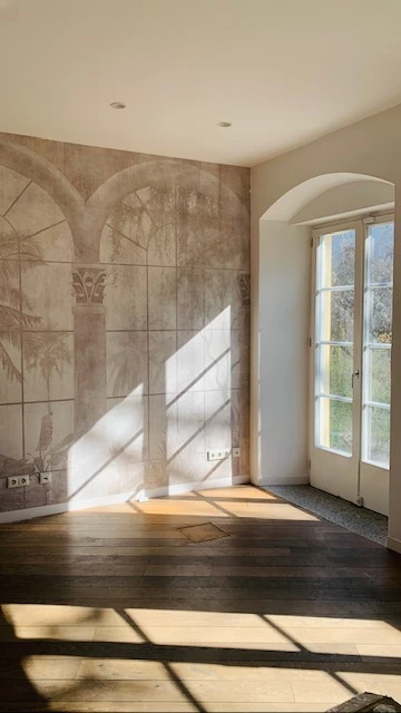 Praxisraum im Schlosspalais No. 1 mit Wandbild, Holzdielen und Flügeltür ins Grüne
